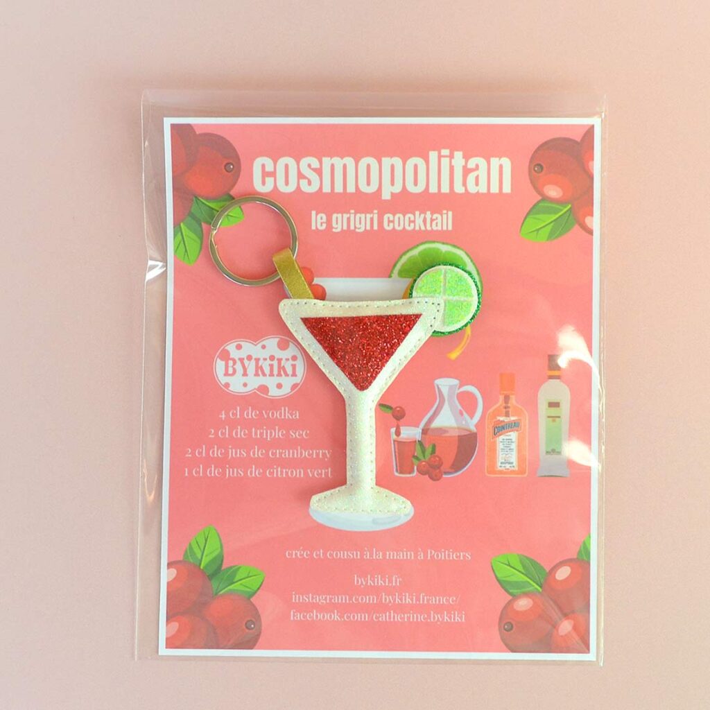 Goodie cocktail Cosmopolitan personnalisé avec porte-clés cousu main et carte recette aimantée, présenté dans une pochette transparente