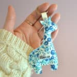 Porte-clés girafe en tissu Liberty bleu tenu dans la main, goodies textile personnalisé pour entreprise