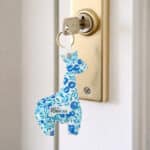 Porte-clés girafe en tissu Liberty bleu accroché à une clé dans une serrure, cadeau client personnalisé
